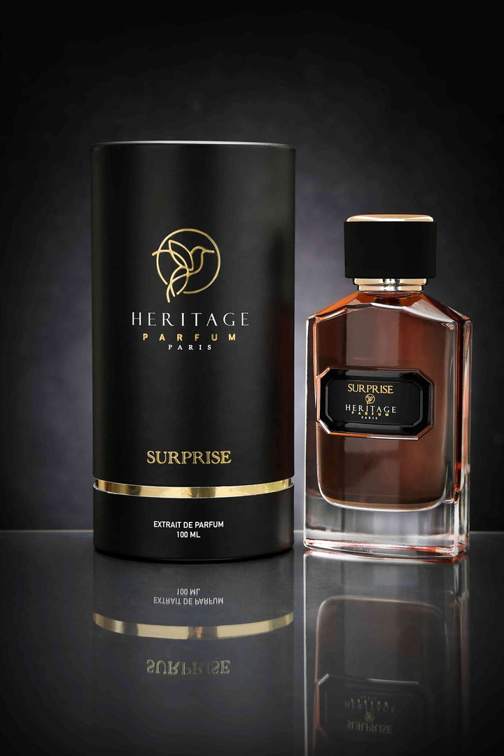 Présentation élégante du parfum 'Surprise' de Heritage Parfum Paris, affichant la boîte noire et la bouteille transparente. Ce parfum pour Homme & Femme, disponible exclusivement chez la meilleure boutique en ligne de parfum en Europe, promet une expérience olfactive mystérieuse et captivante.